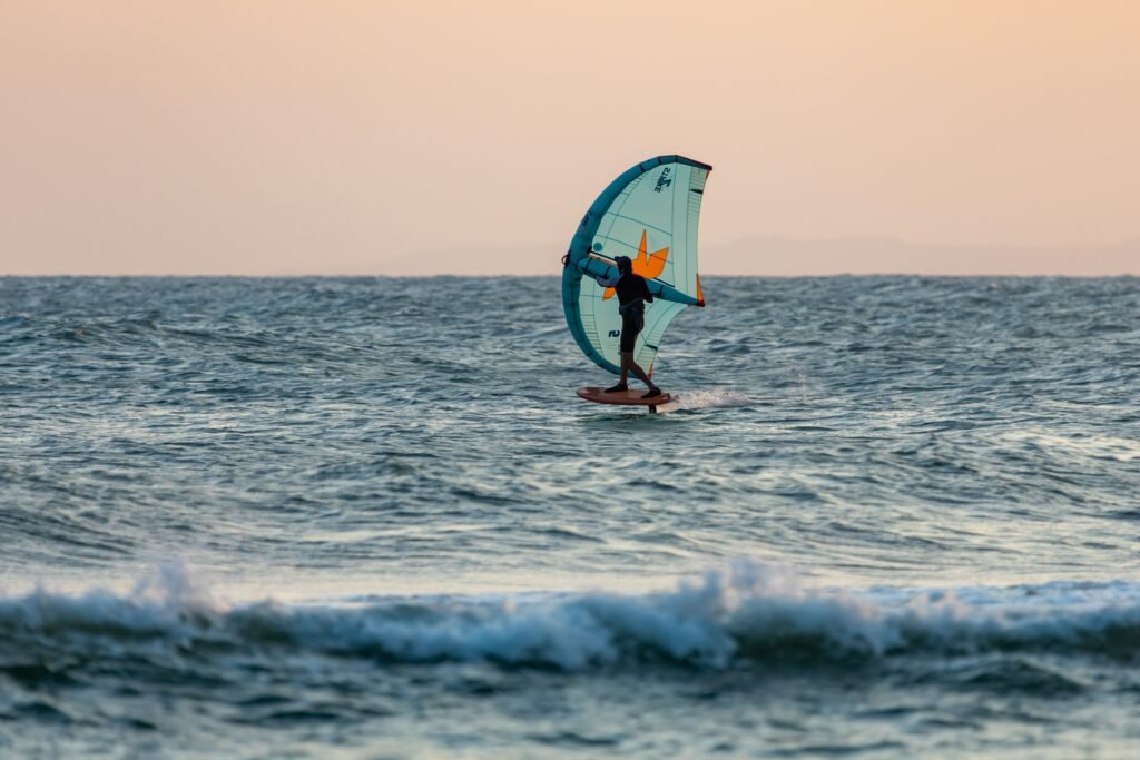 Kitesurfer skillfully riding the waves at sunset in the open ocean.