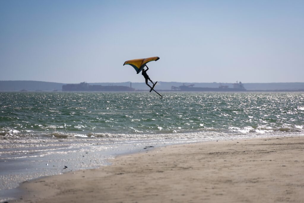A windsurfer skillfully rides the waves on a sunny day at the beach. Captivating ocean adventure.