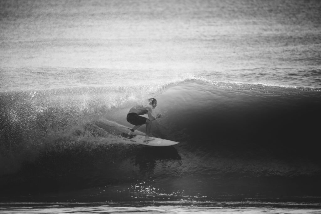 Black and white photo of a surfer riding a wave, capturing the thrill of surfing at sea.