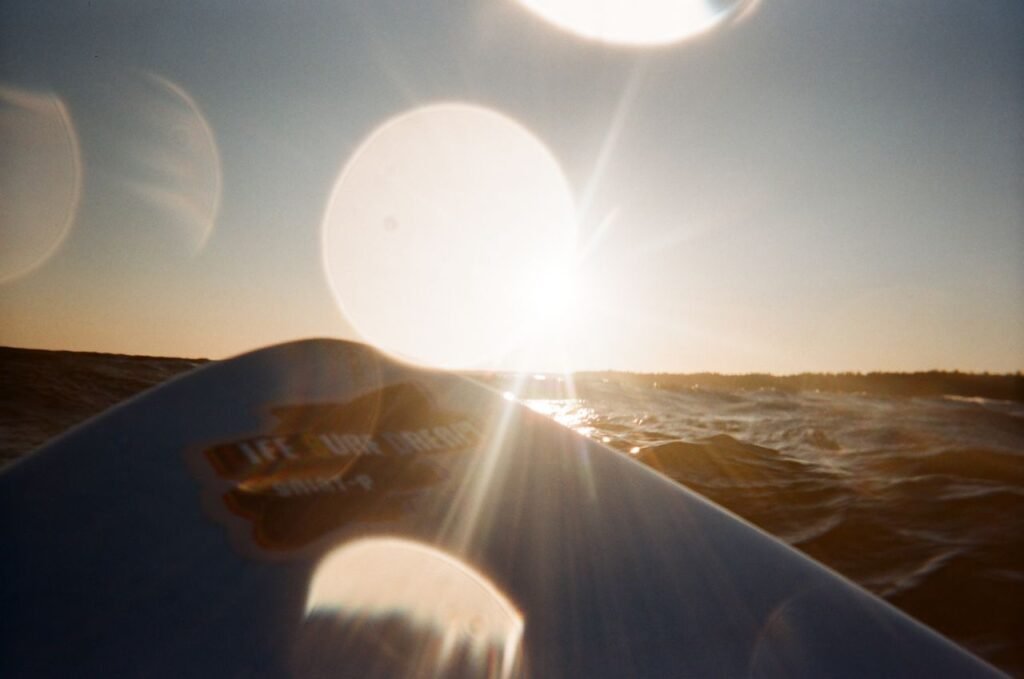 Captivating view of sunset over ocean waves with a surfboard.